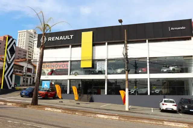 Uma fileira de carros está estacionada em frente a uma concessionária de carros Renault.
