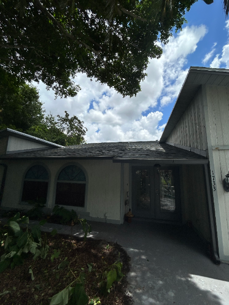Front view of a light-colored house with arched windows, a dark roof, and a walkway.