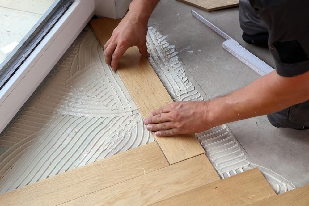 a man is laying a piece of wood on the floor