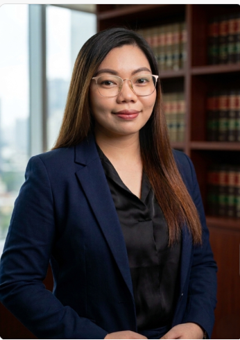Camille Celecio. Woman with glasses and a soft smile, wearing a navy blazer over a black top.