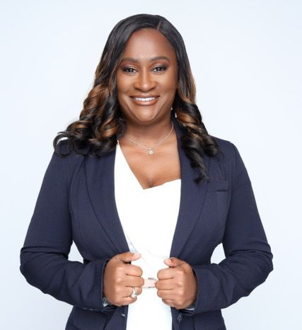 Smiling professional in a navy blazer and white top against a light background