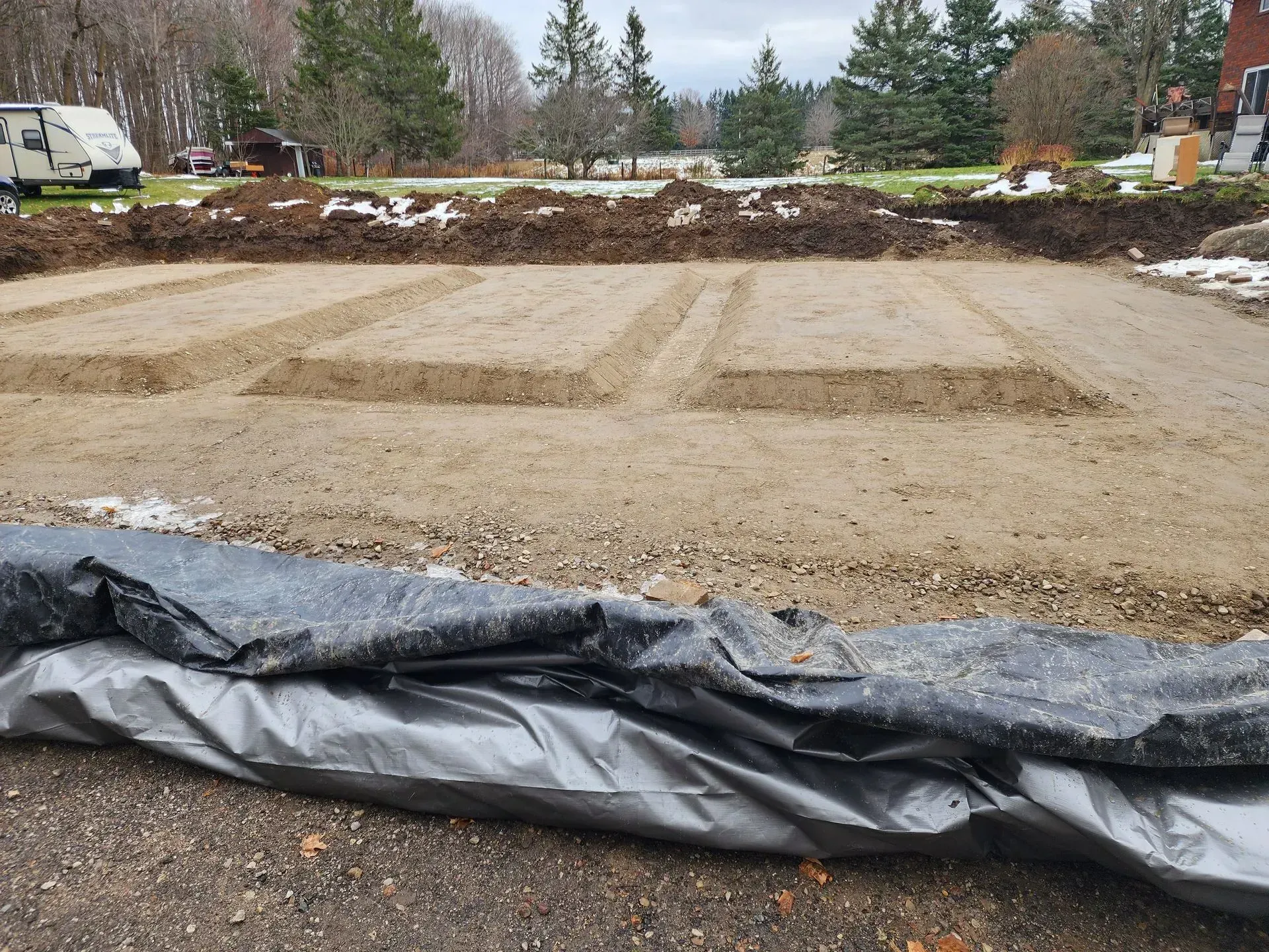 A black tarp is laying on the ground in front of a dirt field.