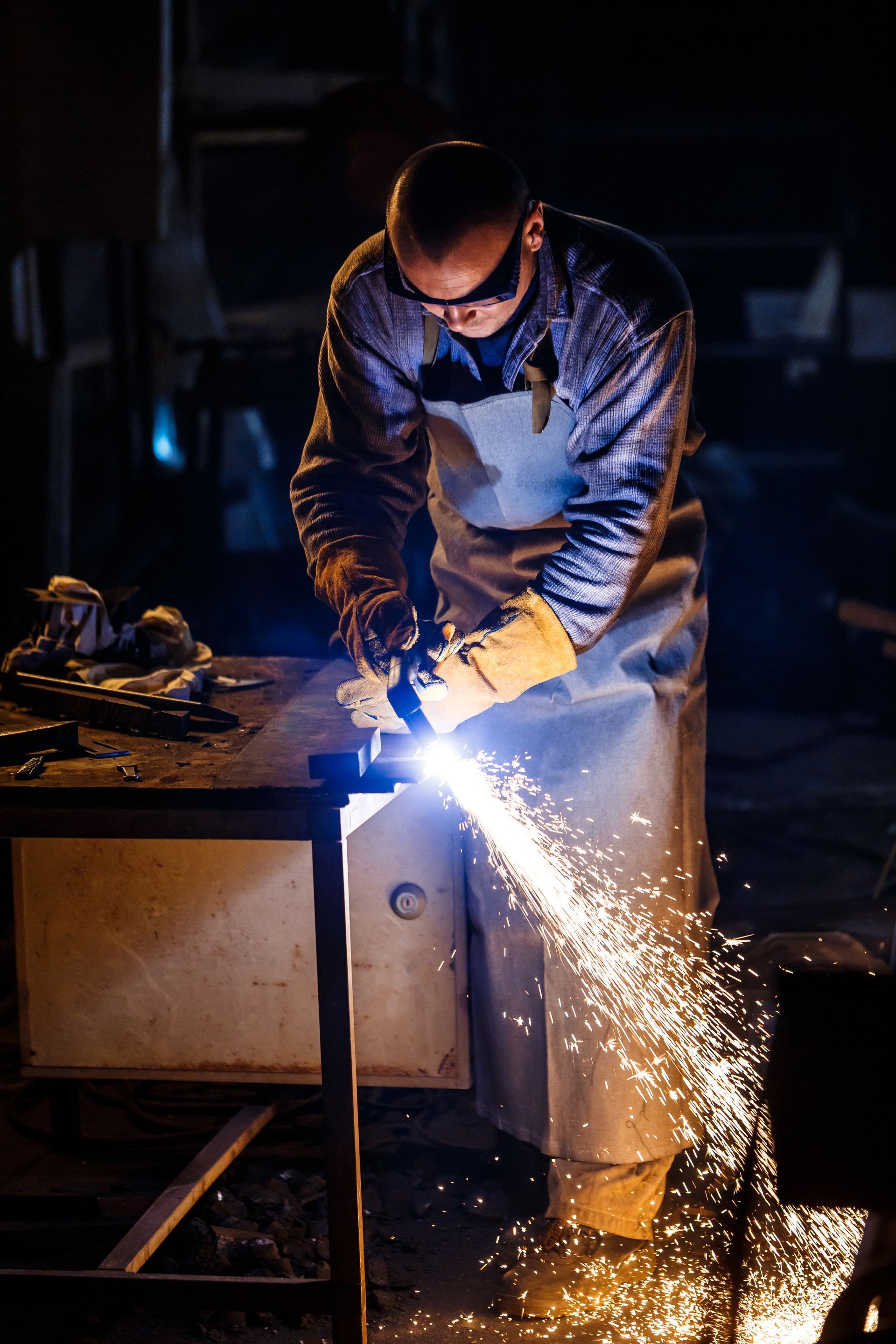A man is cutting a piece of metal with a torch.