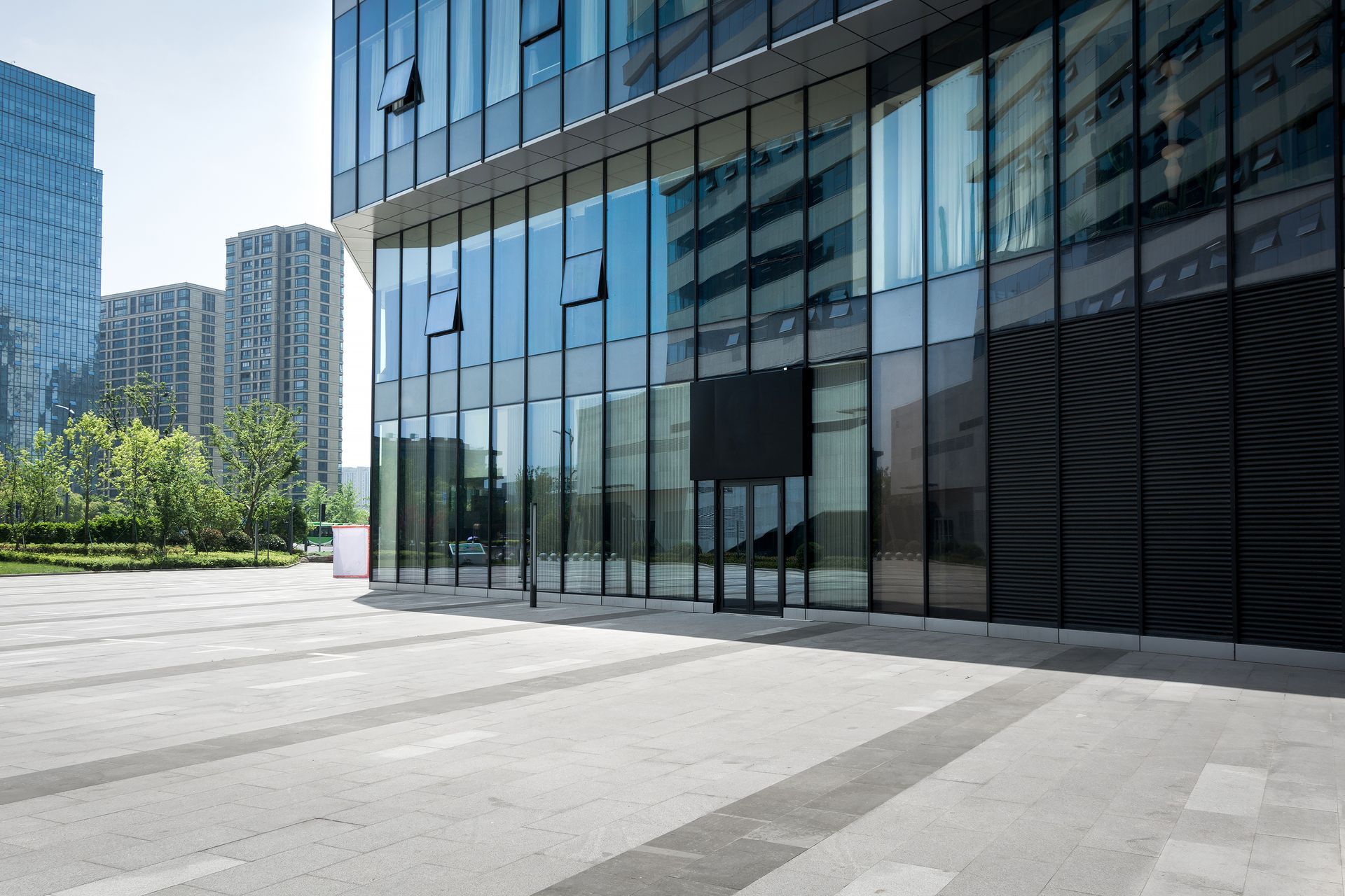 An empty square in front of a tall building with lots of windows.