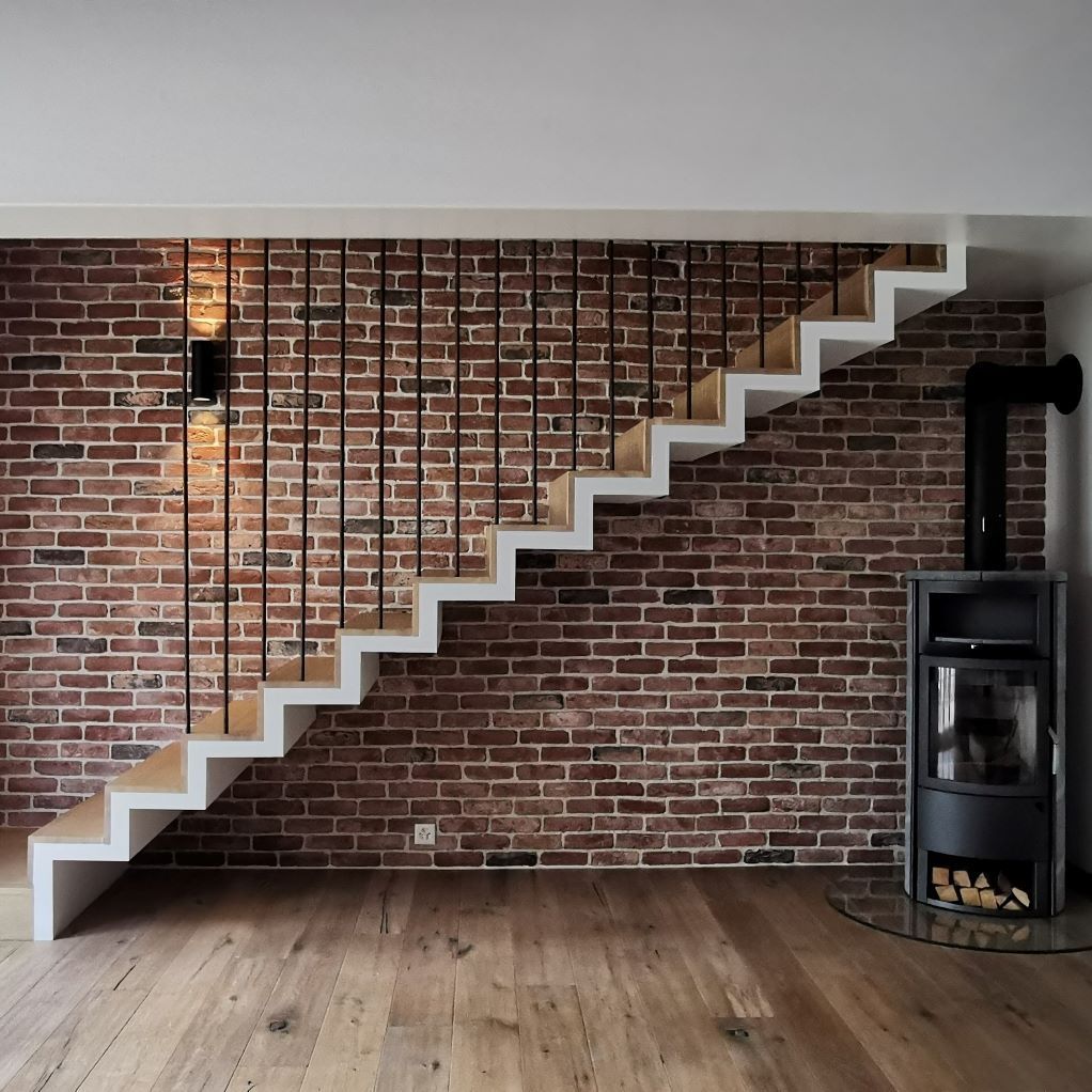 Un escalier en bois avec un mur de briques derrière