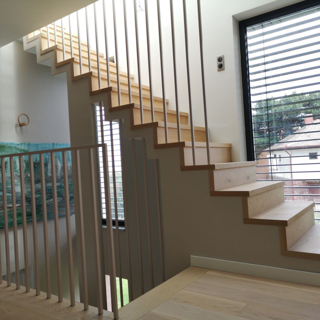 Un escalier en bois avec une rampe en métal et une fenêtre