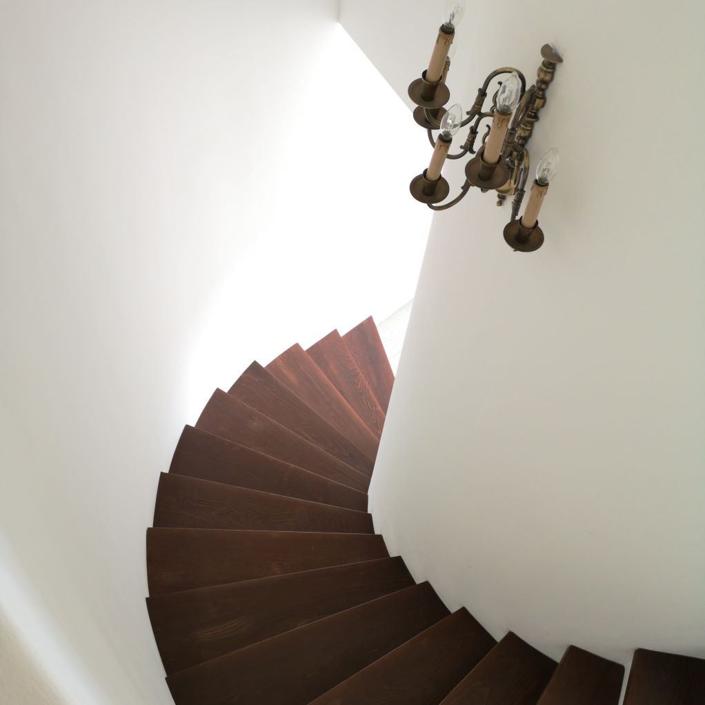 Un escalier en colimaçon avec un lustre suspendu au plafond