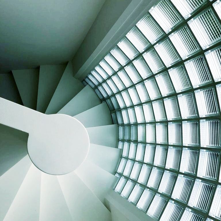 Un escalier en colimaçon avec un mur de verre derrière