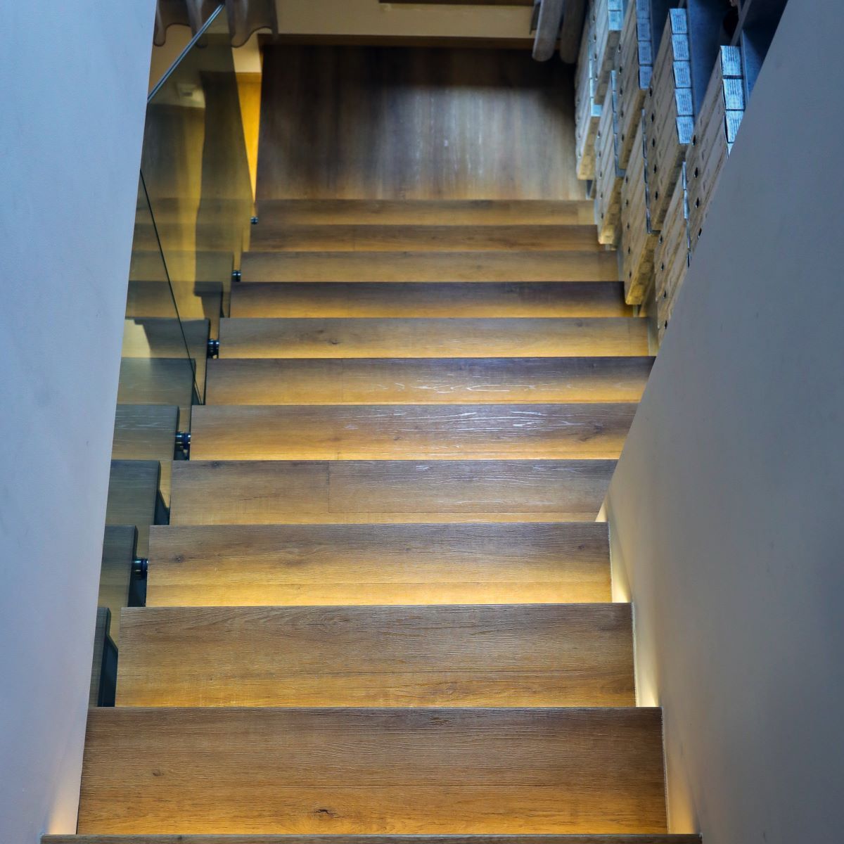 Les escaliers sont en bois et possèdent une rampe en verre.