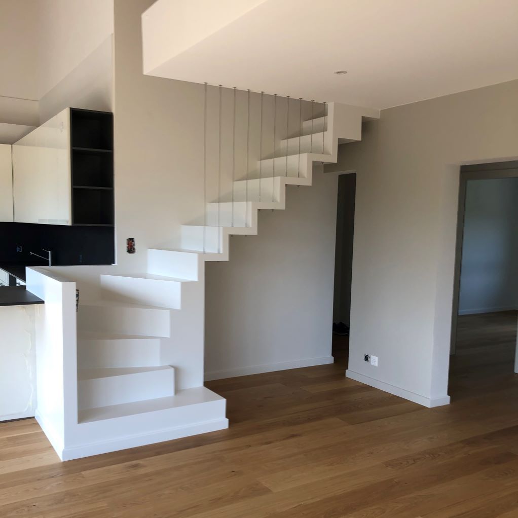 Un escalier blanc dans une pièce vide avec un plancher en bois