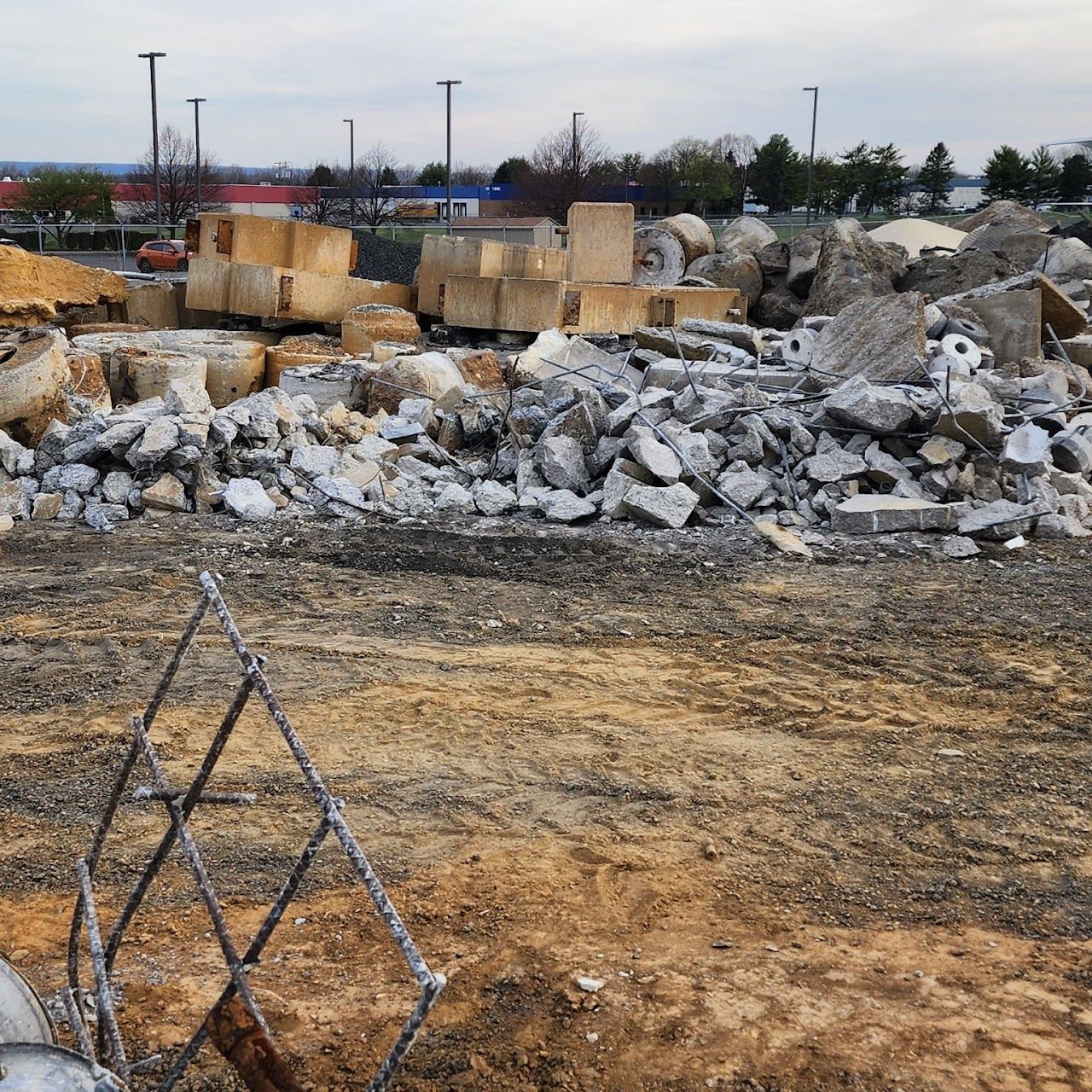 Construction site with concrete debris and a chain-link fence in the foreground.