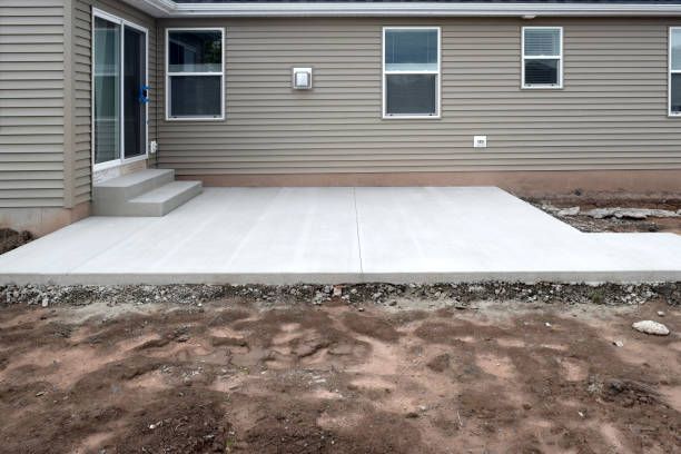 Concrete patio outside a house with a sliding door and steps installed by nto lawn care & landscaping