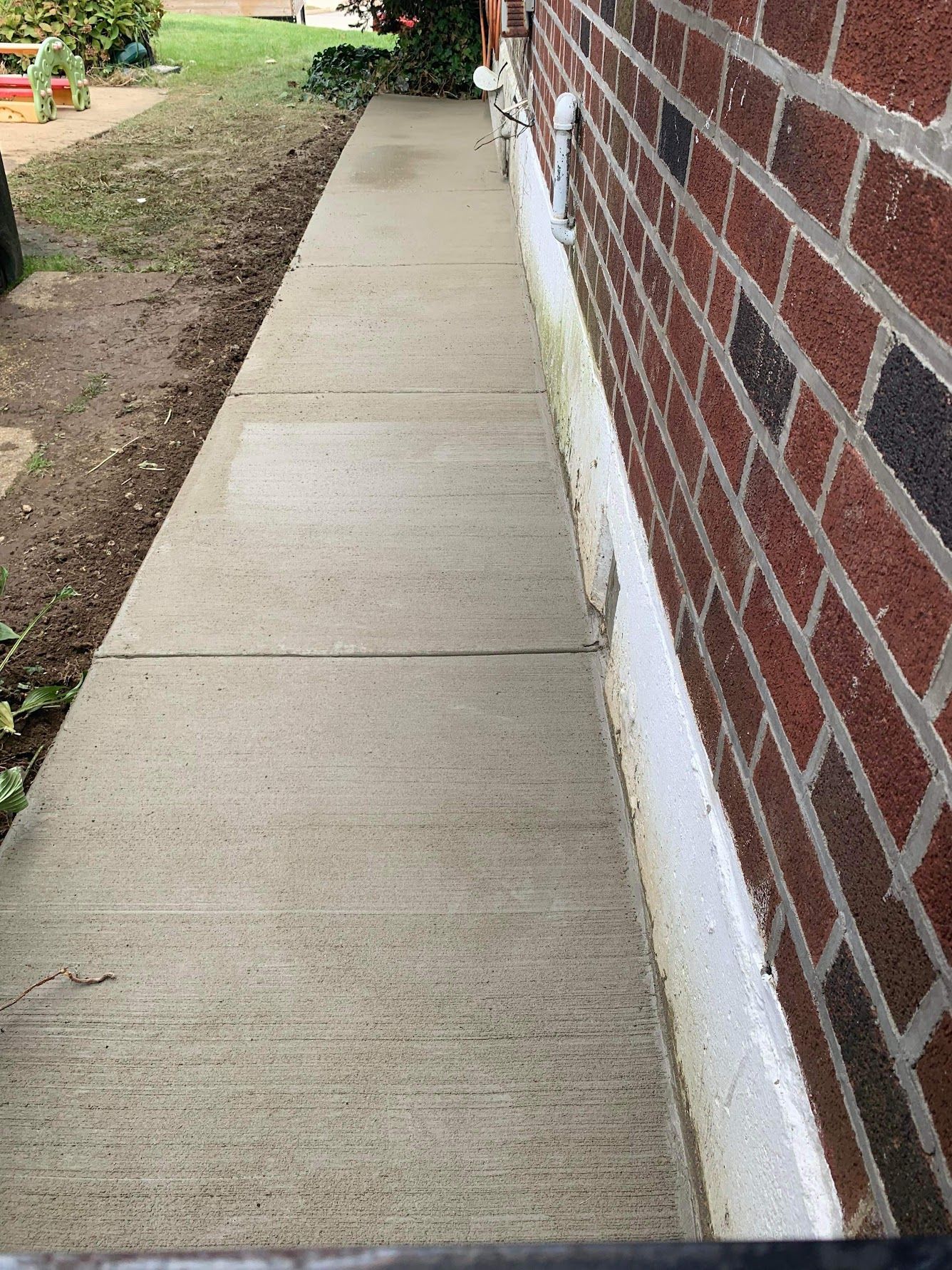 A brick wall with a sidewalk in front of it.