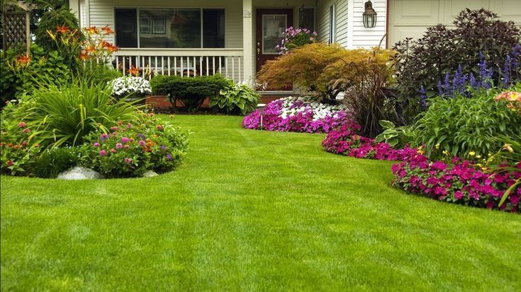 A house with a lush green lawn and flowers in front of it