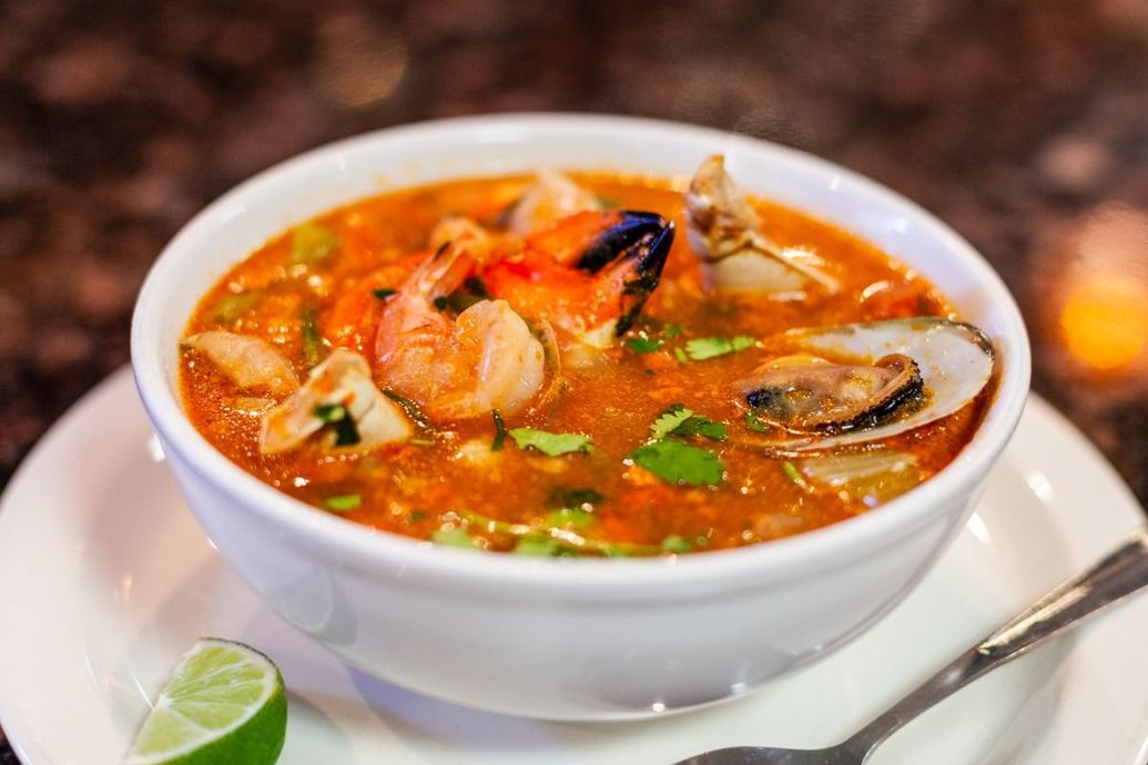 Bowl of seafood soup with shrimp, mussels, and cilantro.