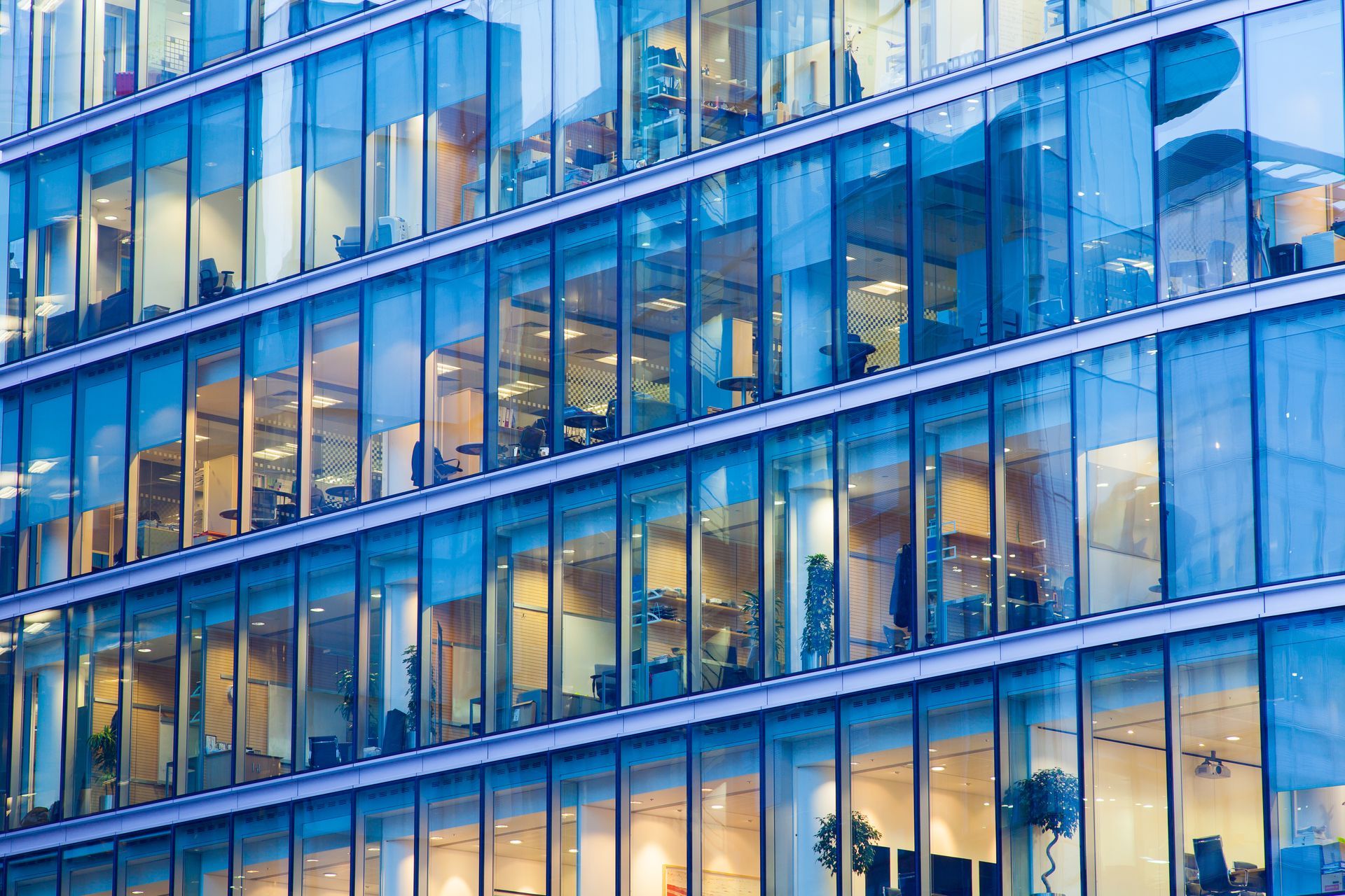 Modern office building with blue-tinted glass facade reflecting light.