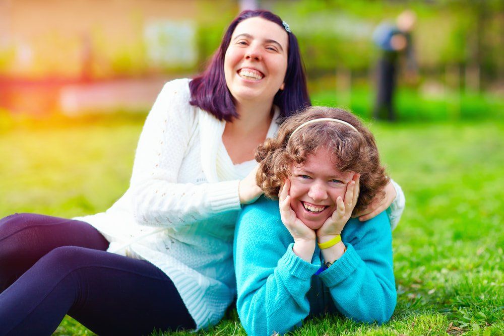 Two Happy Woman With Disability On Spring Lawn — NDIS Services in Yeppoon, QLD
