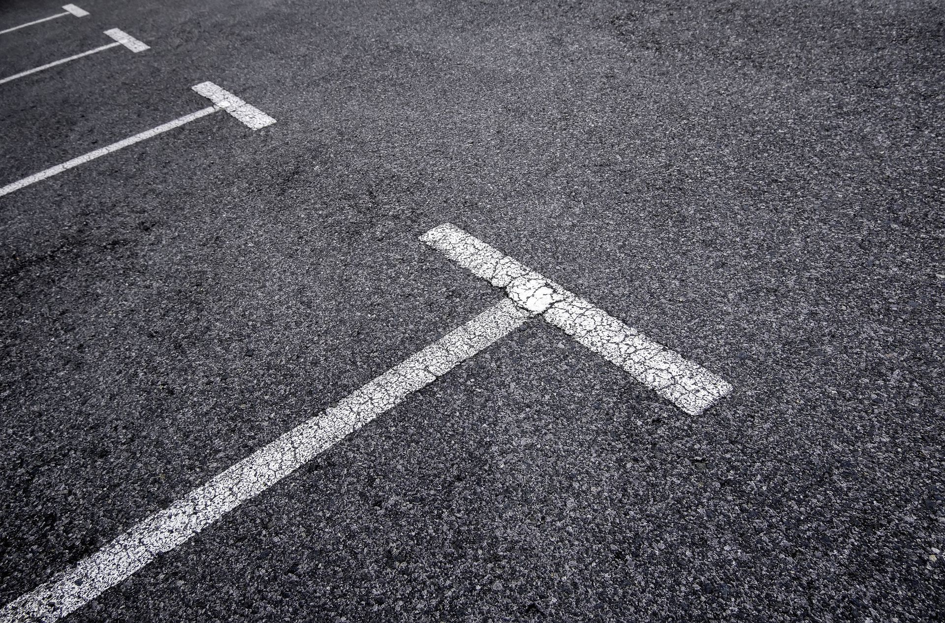 A black and white photo of a parking lot with white lines.