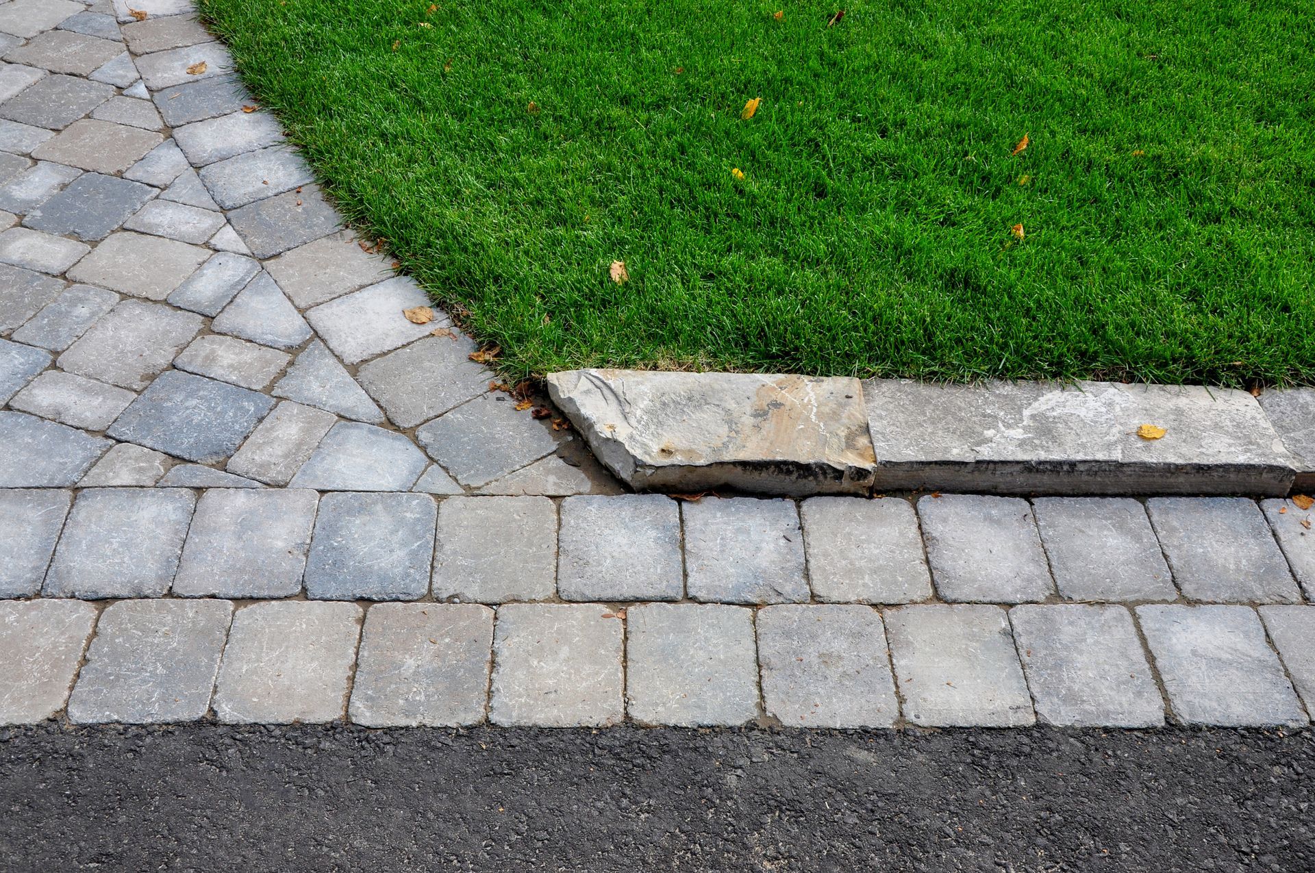 A brick walkway leading to a lush green lawn.
