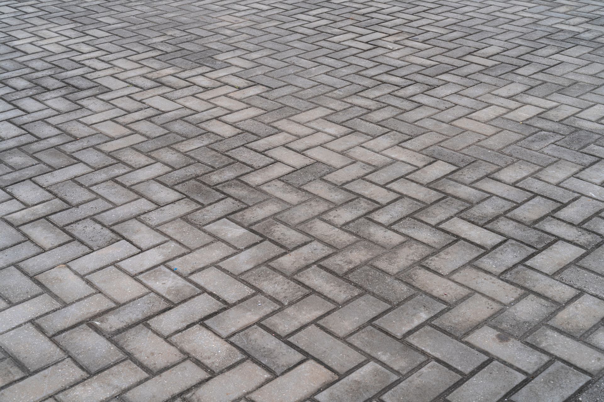 A close up of a brick pavement with a herringbone pattern.