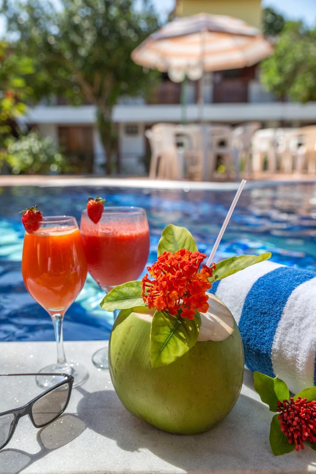 Duas bebidas estão sobre uma toalha ao lado de uma piscina.