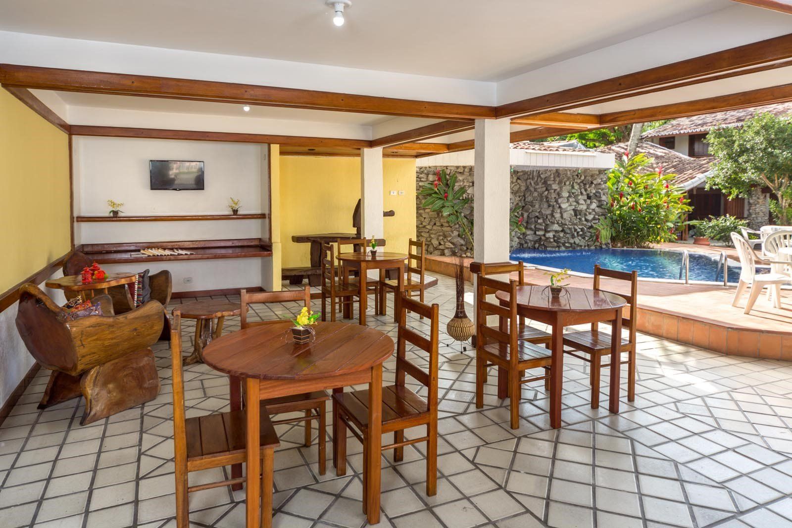 Uma sala com mesas e cadeiras e uma piscina ao fundo