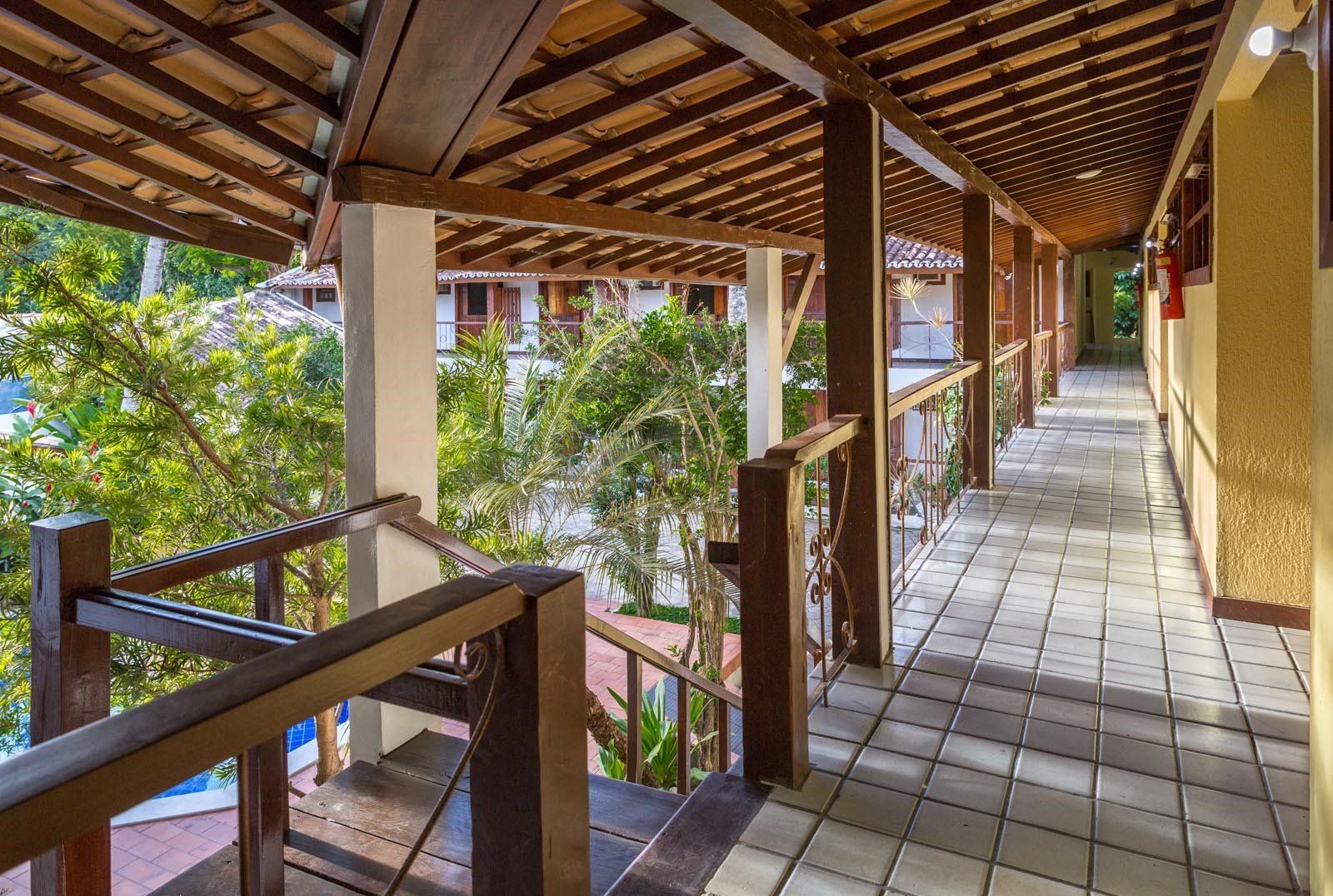 Um longo corredor com grades de madeira e escadas que levam a um prédio.