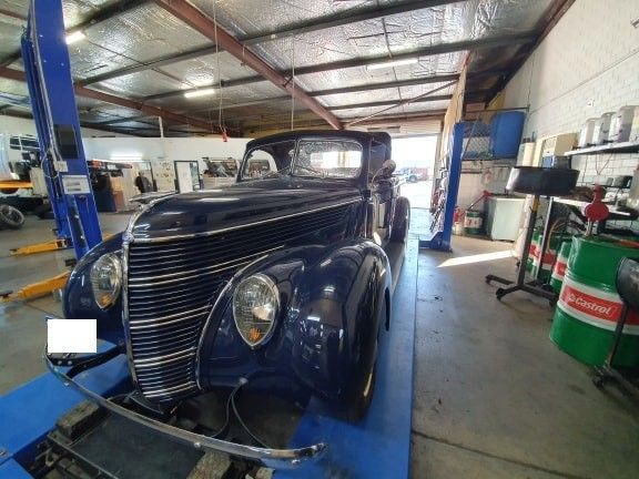 Dark blue vintage car on a lift in a garage.