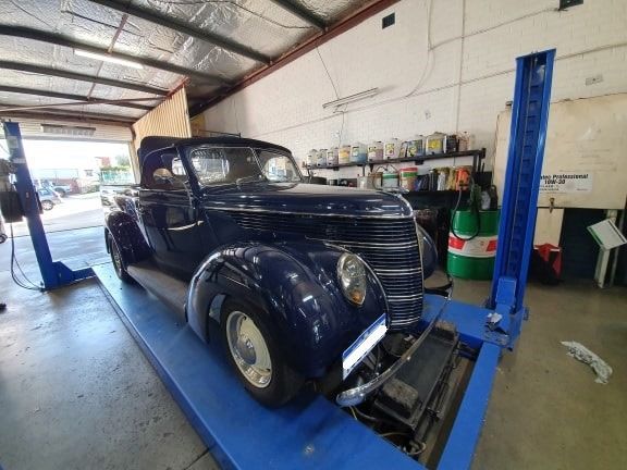 Blue classic car on a blue lift in a garage.