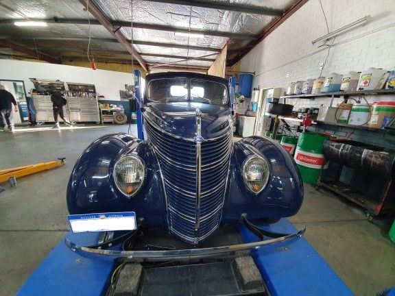 Blue classic car in a garage, facing the viewer.