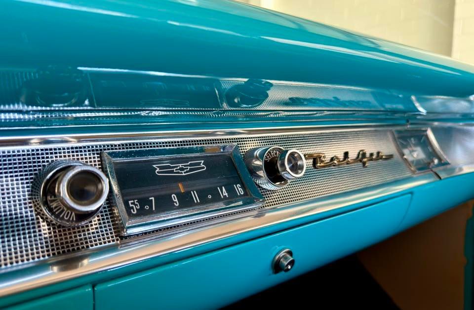 Turquoise dashboard of a classic Chevrolet Bel Air, with chrome accents and radio controls.