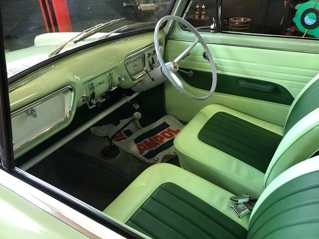 Interior of a light green and dark green classic car; seats, dashboard, and steering wheel visible.