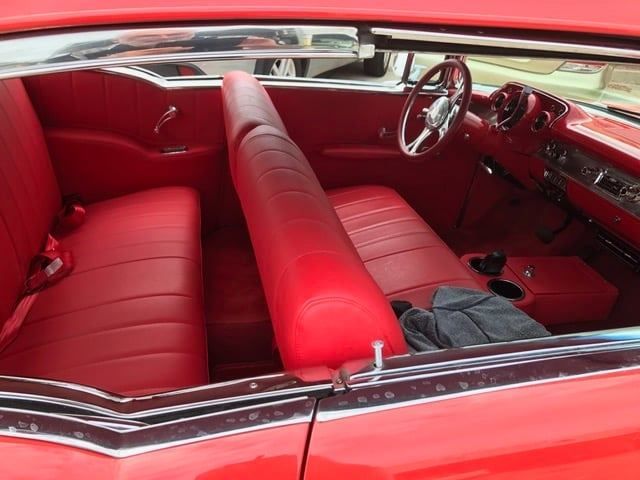 Red car interior with red seats, dashboard, and steering wheel; a classic car.
