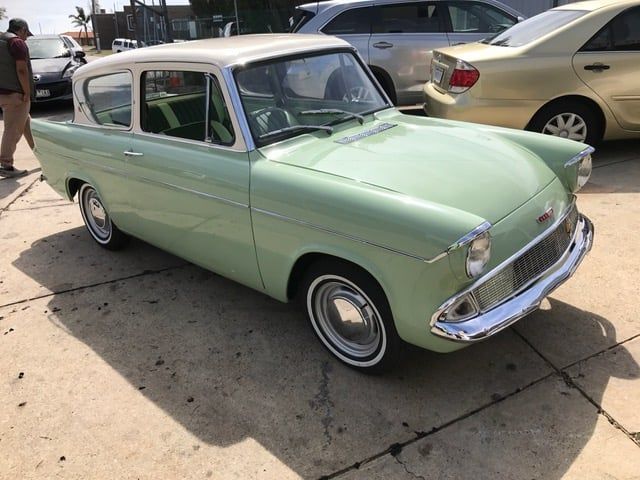 Light green vintage car with a cream top parked outdoors.