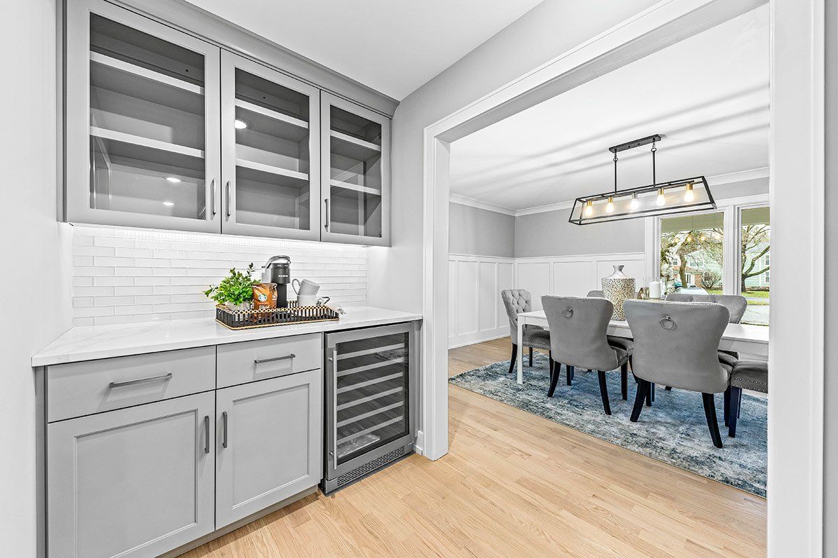 A kitchen with a wine cooler and a dining room in the background.