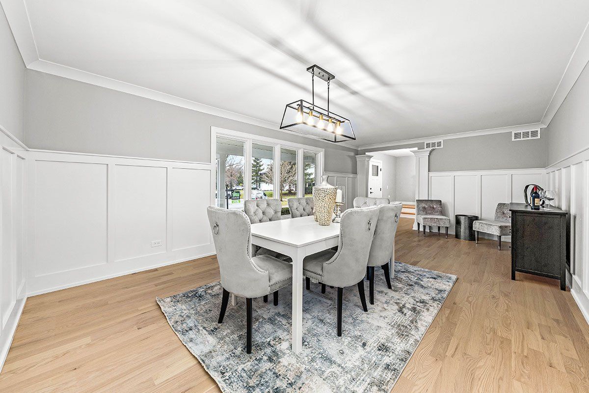 A dining room with a table and chairs and a rug.