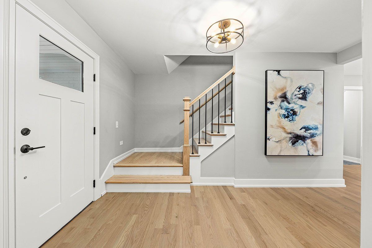 A hallway with stairs and a painting on the wall.