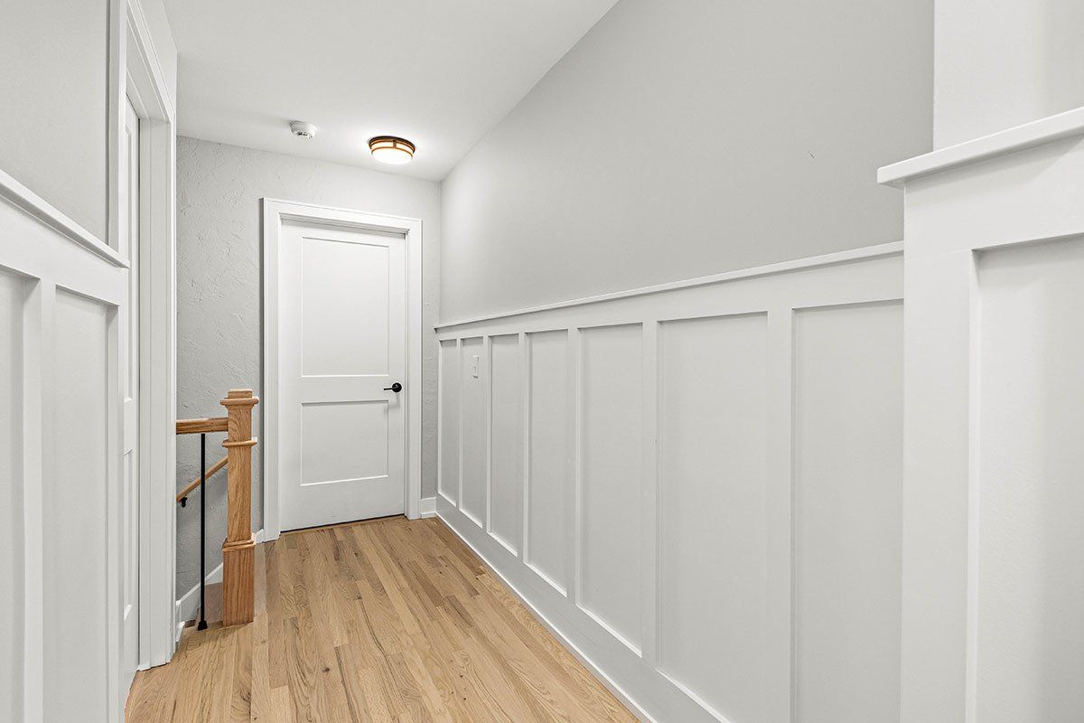 A hallway with white walls and wooden floors in a house.