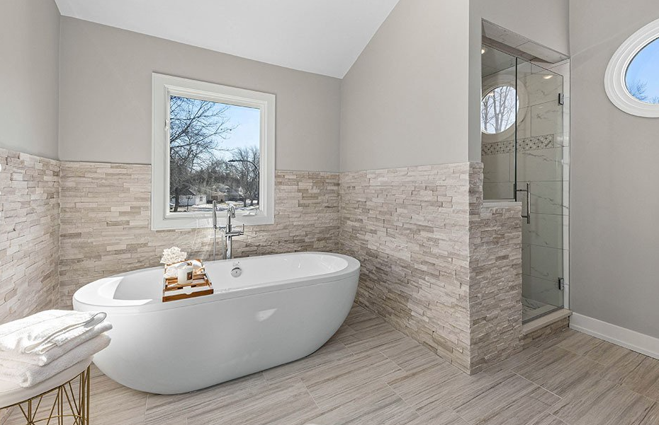 A bathroom with a tub , shower and window.