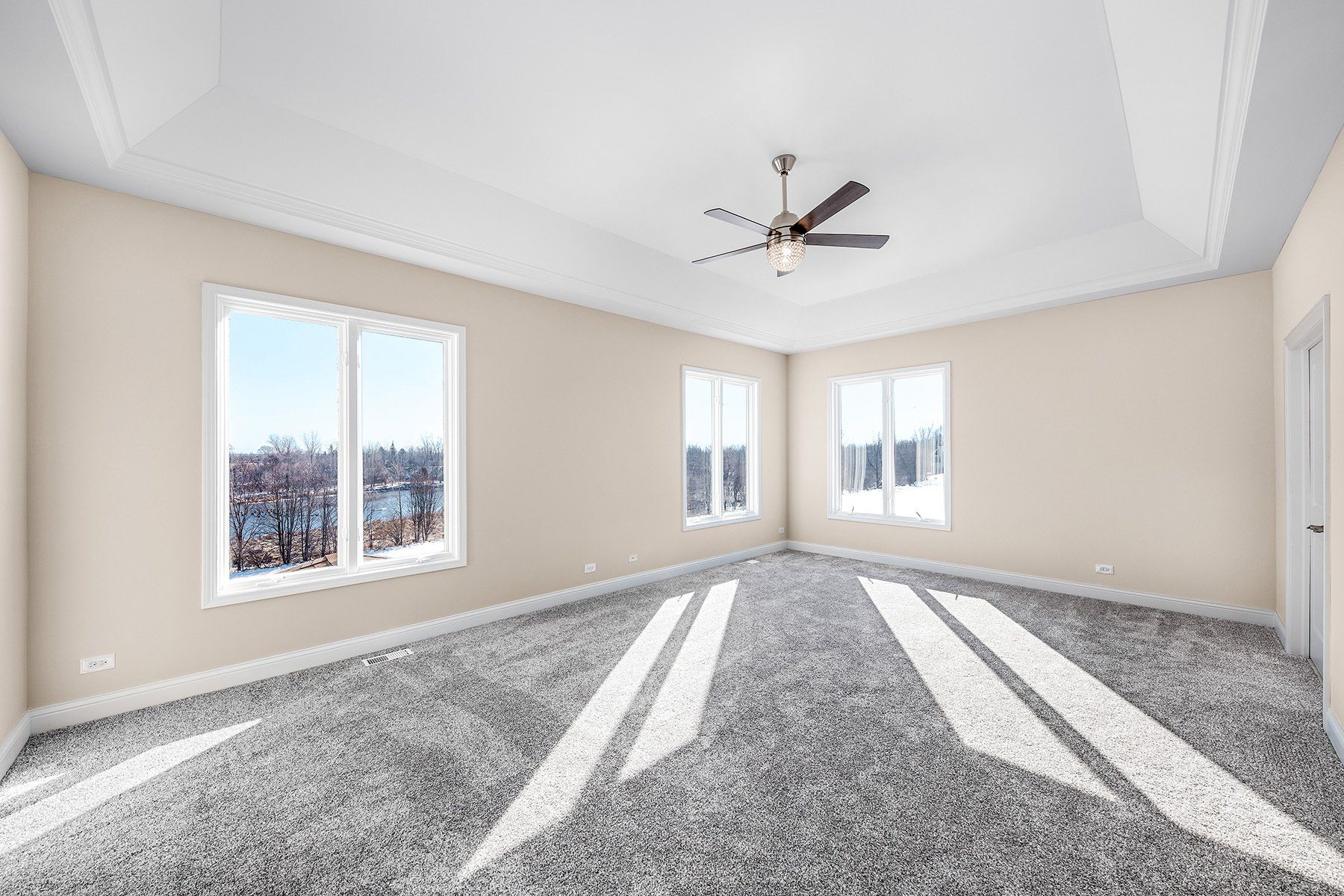 A large empty room with a ceiling fan and a lot of windows.