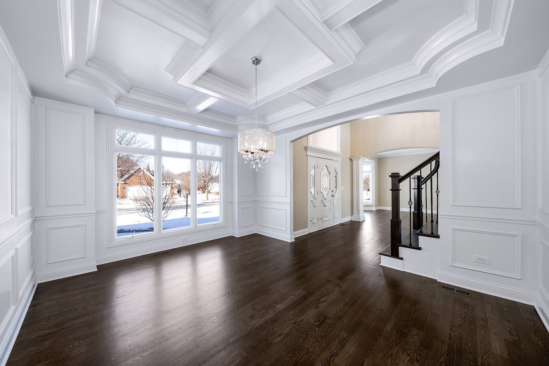 A large empty room with hardwood floors and a chandelier.