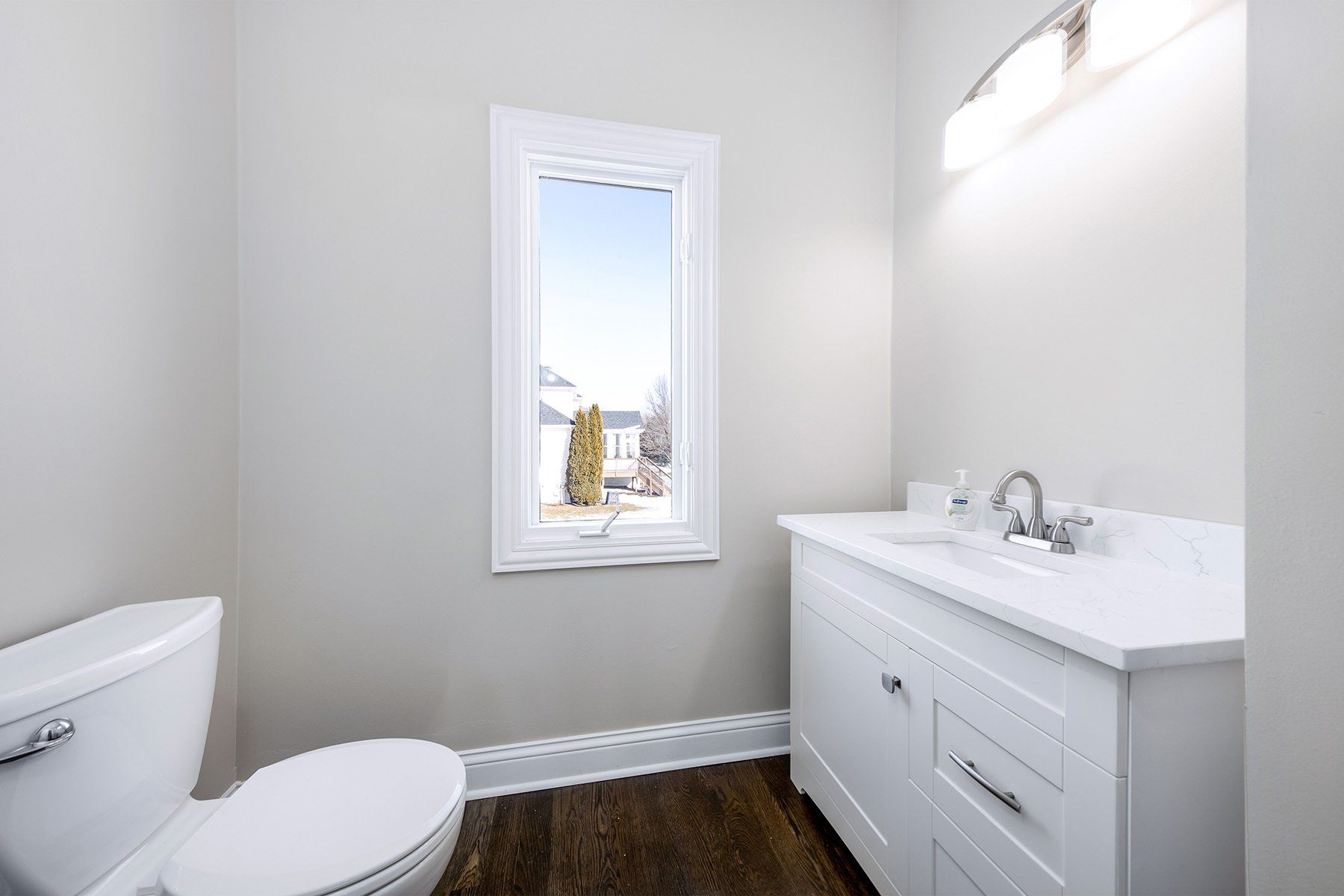 A bathroom with a toilet , sink , and window.