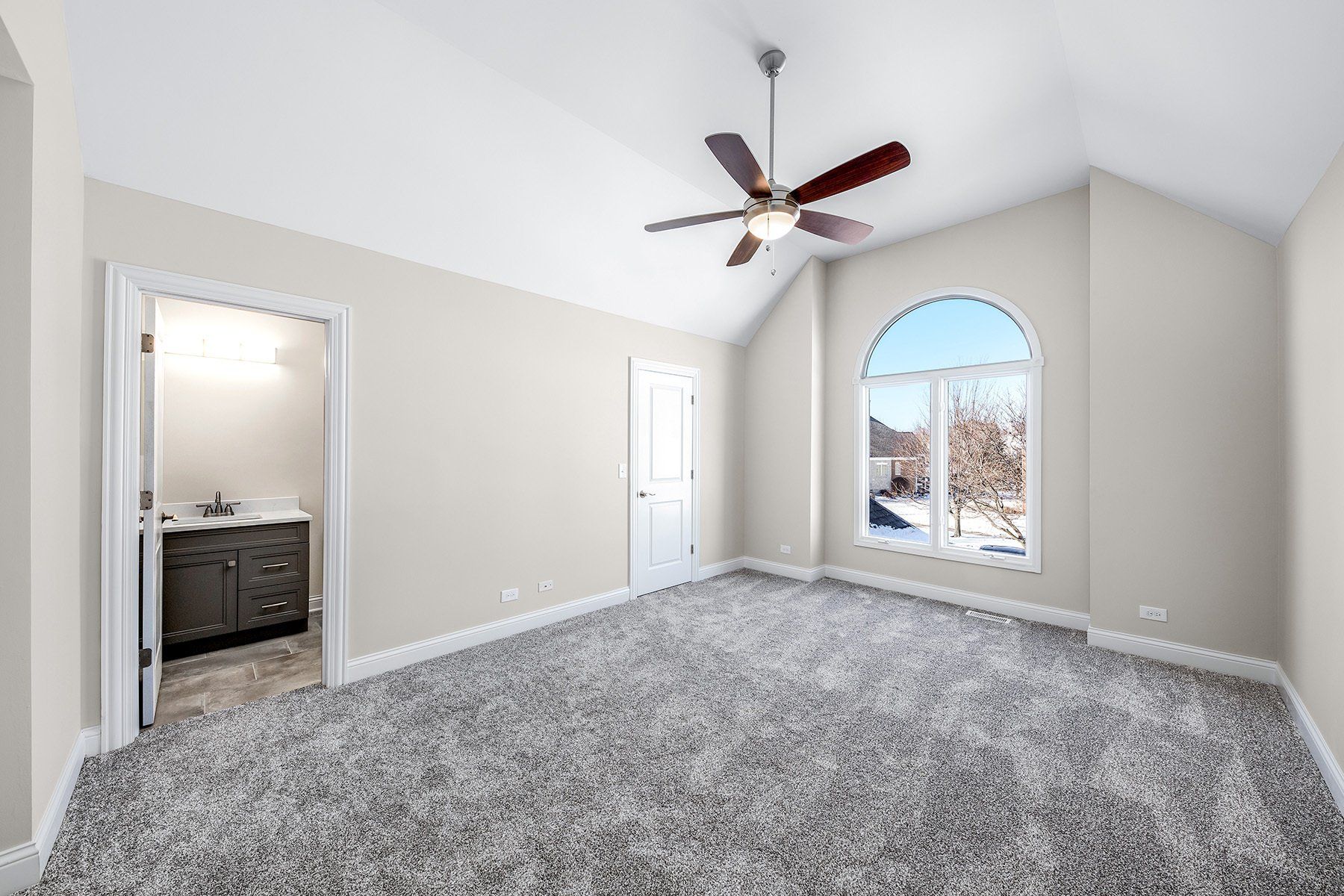 An empty bedroom with a ceiling fan and a large window.