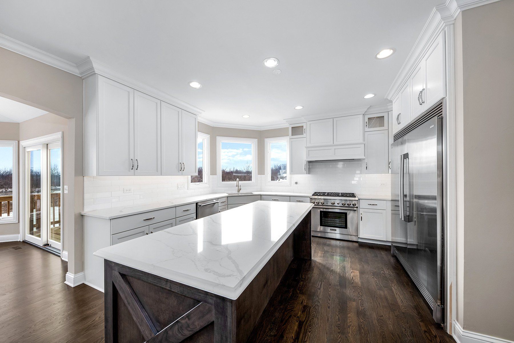 A kitchen with white cabinets , stainless steel appliances , and a large island.