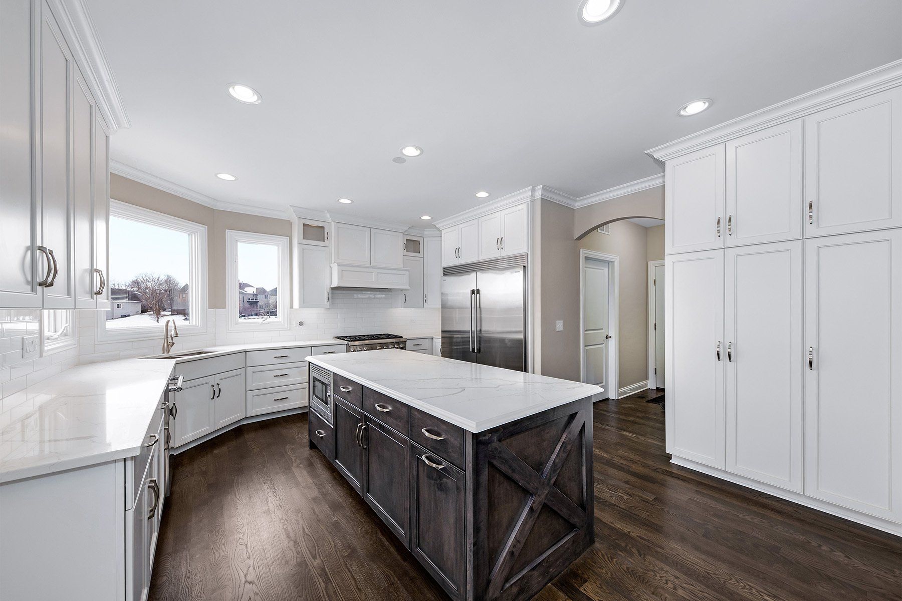 A kitchen with white cabinets and a large island in the middle.