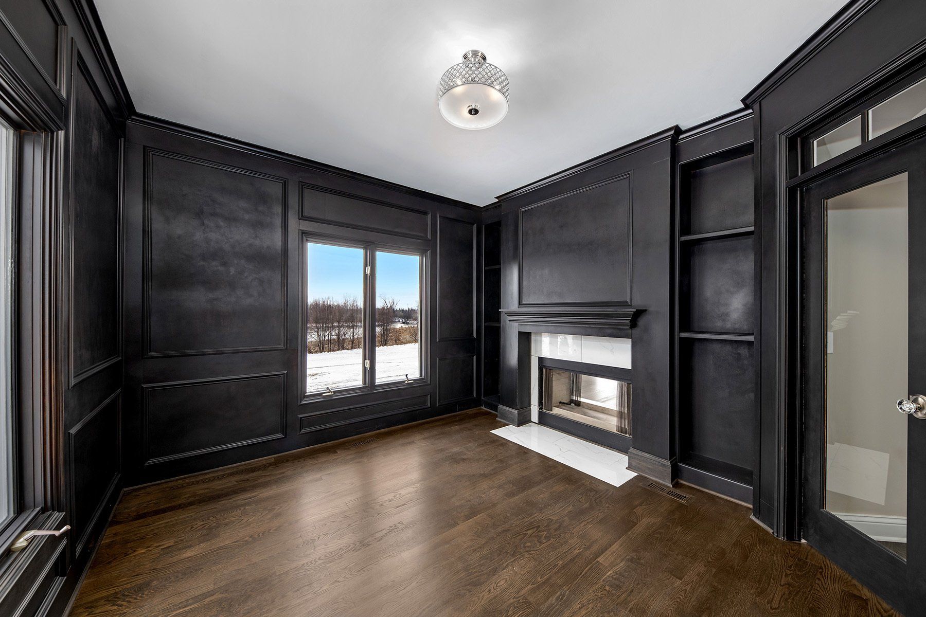An empty living room with black walls and a fireplace.