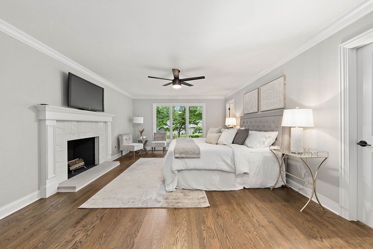 A bedroom with a large bed , fireplace and television.