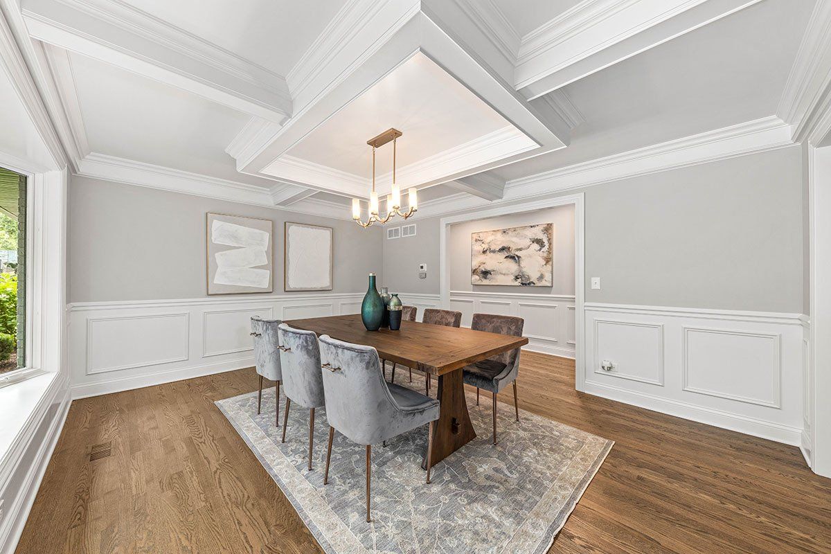 A dining room with a wooden table and chairs and a chandelier.
