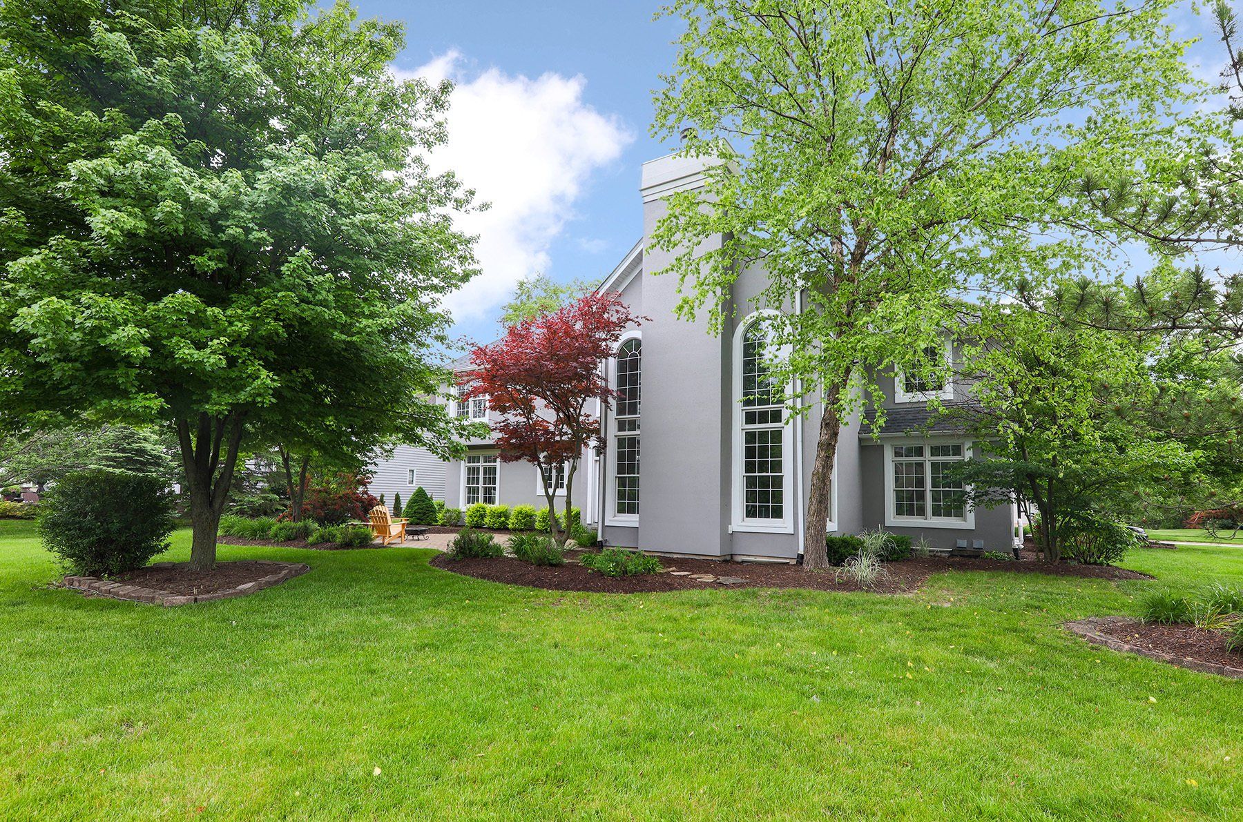 A house with a large lawn and trees in front of it.