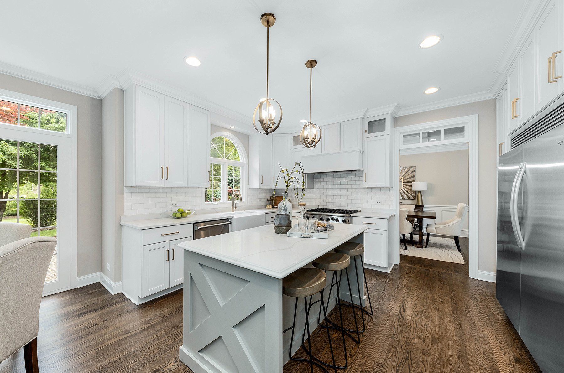 A kitchen with white cabinets and stainless steel appliances and a large island in the middle.